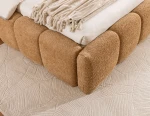 Detailansicht der Rahmenverbindung und der Füße des Designer-Bettes Sorento (140x200 cm), bezogen mit hellem Bouclé-Material.