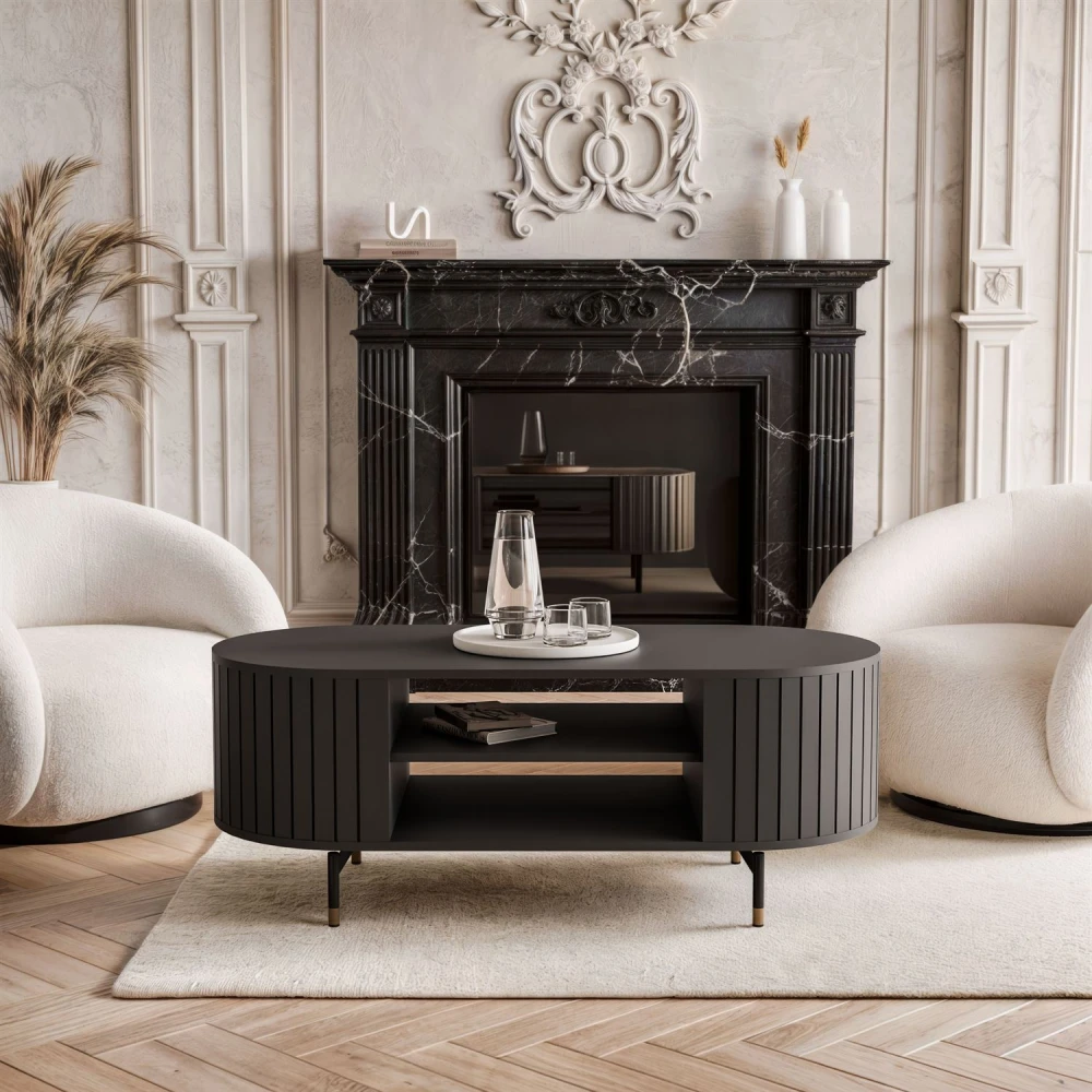 Schräge Ansicht des ovalen Couchtisches Linnea (104 cm) in Schwarz Matt mit praktischer Ablage, goldenen Füßen und Lamellen-Design, freigestellt auf weißem Hintergrund.