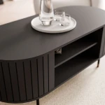 Seitenansicht des modernen Couchtisches Linnea in tiefem Schwarz, die den offenen Stauraum der Ablage unter der Tischplatte perfekt präsentiert.