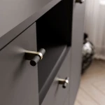 Das Sideboard Linnea in Schwarz mit geöffneten Türen und Schubladen, welches das praktische Stauraumkonzept und die offenen Fächer in der Mitte präsentiert.