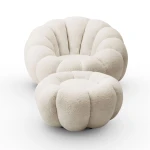 Klassische Ansicht des eleganten Drehsessels ORIA mit Hocker aus beigefarbenem Bouclé-Material, freigestellt auf einem neutralen, weißen Hintergrund.