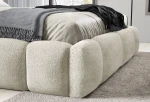 Detailansicht des abgerundeten Fußteils vom Bett ABIK, die die dichte Teddy-Struktur des Bouclé-Bezugs Coral 15 hervorhebt.