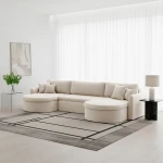 Stilvoll eingerichteter Wohnbereich mit dem cremefarbenen Bouclé-Sofa VERONA U Quelle 02 vor hellen Fenstern.