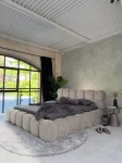 inladendes Schlafzimmer-Ambiente mit dem Hellgraubeige Polsterbett 140x200 Cloudi im samtigen Bezug Lumo (Chenille), stilvoll dekoriert mit grauer Bettwäsche und Kuscheldecke.