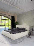inladendes Schlafzimmer-Ambiente mit dem Creme Polsterbett 140x200 Cloudi im samtigen Bezug Lumo (Chenille), stilvoll dekoriert mit grauer Bettwäsche und Kuscheldecke.