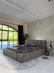 inladendes Schlafzimmer-Ambiente mit dem Graphit Polsterbett 140x200 Cloudi im samtigen Bezug Lumo (Chenille), stilvoll dekoriert mit grauer Bettwäsche und Kuscheldecke.