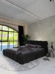 inladendes Schlafzimmer-Ambiente mit dem Schwarz Polsterbett 140x200 Cloudi im samtigen Bezug Lumo (Chenille), stilvoll dekoriert mit grauer Bettwäsche und Kuscheldecke.
