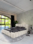 inladendes Schlafzimmer-Ambiente mit dem Elfenbein Polsterbett 160x200 Cloudi im samtigen Bezug Lumo (Chenille), stilvoll dekoriert mit grauer Bettwäsche und Kuscheldecke.