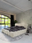 inladendes Schlafzimmer-Ambiente mit dem Hellbeige Polsterbett 180x200 Cloudi im samtigen Bezug Lumo (Chenille), stilvoll dekoriert mit grauer Bettwäsche und Kuscheldecke.
