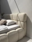 Nahaufnahme des gepolsterten Kopfteils des Betts DIEGO (160x200 cm), welche die feine und gemütliche Textur des Coral Bouclé-Stoffes im Detail präsentiert.