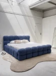 Schräge Ansicht des französischen Polsterbetts DIEGO (160x200 cm) in Coral 05 Bouclé, stilvoll arrangiert und harmonisch integriert in eine moderne Schlafzimmerumgebung.