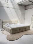 Schräge Ansicht des französischen Polsterbetts DIEGO (160x200 cm) in Coral 15 Bouclé, stilvoll arrangiert und harmonisch integriert in eine moderne Schlafzimmerumgebung.