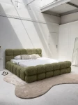 Schräge Ansicht des französischen Polsterbetts DIEGO (160x200 cm) in Coral 25 Bouclé, stilvoll arrangiert und harmonisch integriert in eine moderne Schlafzimmerumgebung.