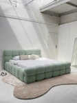 Schräge Ansicht des französischen Polsterbetts DIEGO (160x200 cm) in Coral 55 Bouclé, stilvoll arrangiert und harmonisch integriert in eine moderne Schlafzimmerumgebung.