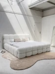 Schräge Ansicht des französischen Polsterbetts DIEGO (160x200 cm) in Coral 70 Bouclé, stilvoll arrangiert und harmonisch integriert in eine moderne Schlafzimmerumgebung.
