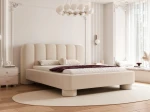Schräge Ansicht des Designer-Polsterbettes Panola (180x200 cm) im hellen Bezug, die das Paneel-Kopfteil und die zylindrischen Beine zeigt, elegant arrangiert in einem hellen Schlafzimmer mit Stuck und einem ovalen Teppich. im RUNO_07