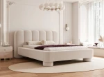 Schräge Ansicht des Designer-Polsterbettes Panola (180x200 cm) im hellen Bezug, die das Paneel-Kopfteil und die zylindrischen Beine zeigt, elegant arrangiert in einem hellen Schlafzimmer mit Stuck und einem ovalen Teppich. im ABRIAMO_03