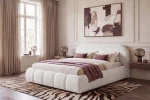 Seitenansicht des beigen Polsterbettes Dakota slim (180x200 cm) im flauschigen Bouclé-Stoff Quelle in einem elegant eingerichteten Schlafzimmer mit großer Holzwand.