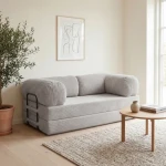 Gemütliches Schlafsofa MUNO aus Poso Cord Stoff mit den Maßen 200x100 cm, stilvoll arrangiert in einem hellen Wohnzimmer.
