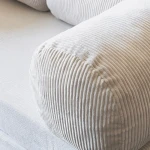 Nahaufnahme der Armlehne des 200x100 cm großen Schlafsofas MUNO, die die weiche Rippenstruktur des Poso Cord Stoffes zeigt.