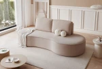 Stilvolles Wohnambiente mit dem geschwungenen Sofa in edlem Riviera Velour, ergänzt durch moderne Beistelltische und helle Dekoration.