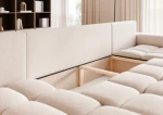 Das ausgeklappte Schlafsofa der Wohnlandschaft OFI U (318x145 cm) aus Bouclé-Stoff mit geöffnetem, integriertem Bettkasten für zusätzlichen Stauraum.