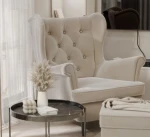 Frontalansicht des Design Ohrensessels SCANDI mit passendem Hocker, bezogen mit edlem Samt Trinity, stilvoll arrangiert in einem modernen Wohnzimmer.