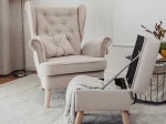 Das gemütliche Ohrensessel CLASSIC Set mit passendem Hocker aus Samt Trinity, ideal positioniert für entspannte Lesestunden im Wohnbereich.