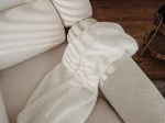 Nahaufnahme der Polsterung des Sessels LILA, welche die gemütliche und feine Textur des Bouclé-Stoffes im Detail präsentiert.