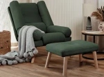 Frontalansicht des Sessels LILA inklusive Hocker mit weichem Samt Trinity Bezug, stilvoll arrangiert in einem modernen Wohnzimmer.