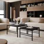 Frontalansicht des modernen Couchtisch-Sets FORMA 2in1 mit markantem schwarzem Gestell, stilvoll arrangiert in einem gemütlichen Wohnzimmer.