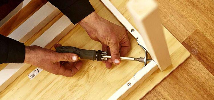 Person liest aufmerksam die Schritt-für-Schritt Montageanleitung beim Aufbau eines Holzschrankes